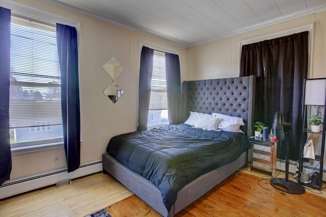 bedroom featuring crown molding, baseboard heating, and wood finished floors