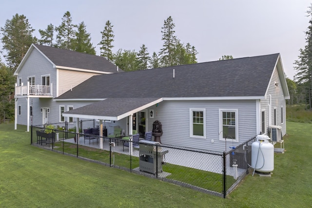rear view of house with a lawn, roof with shingles, and fence