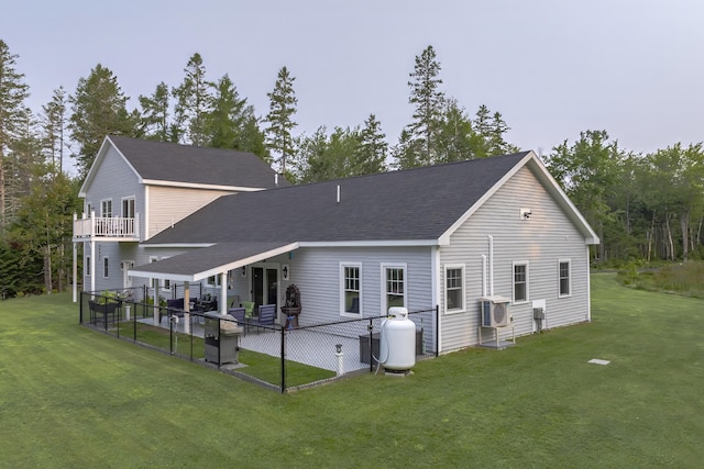 back of house featuring a lawn, roof with shingles, a patio, and ac unit