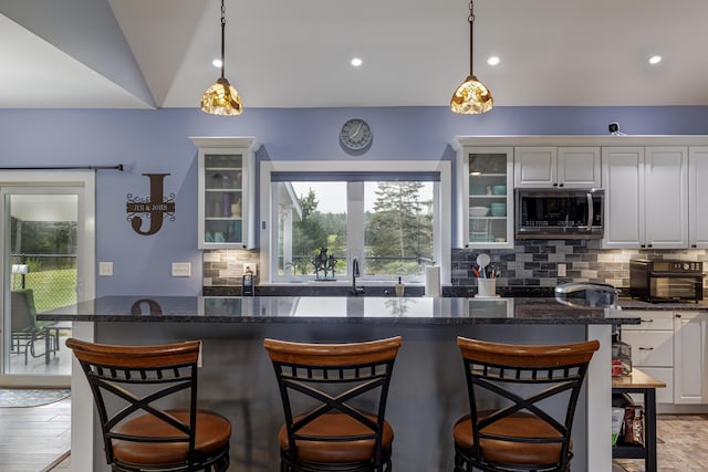 kitchen with stainless steel microwave, white cabinets, and a wealth of natural light