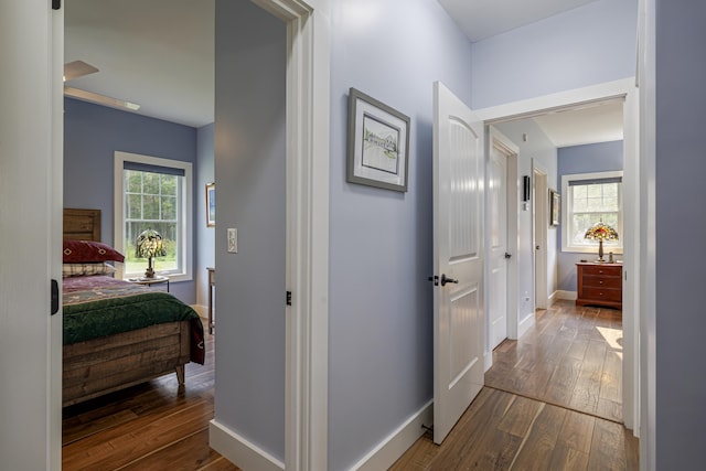 corridor with dark wood-style flooring and baseboards
