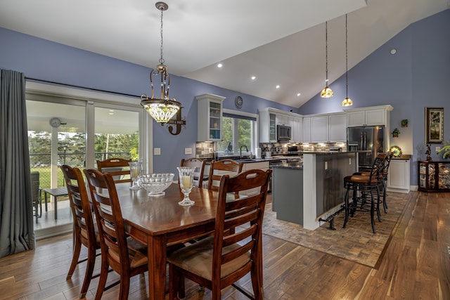 dining room with a notable chandelier, recessed lighting, dark wood-style flooring, and high vaulted ceiling