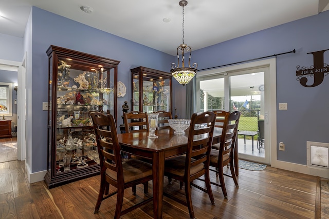dining space with wood finished floors, a notable chandelier, and baseboards