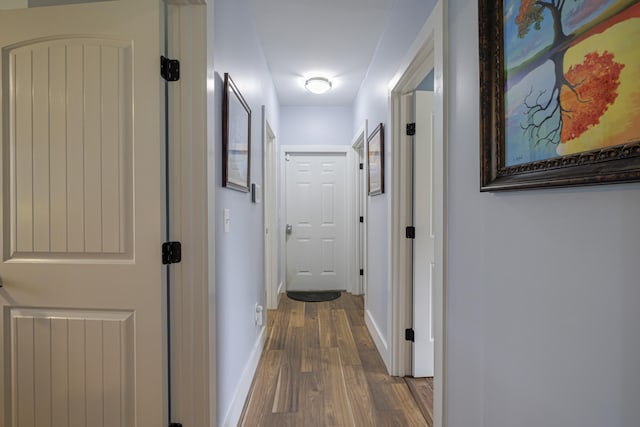 corridor with baseboards and wood finished floors