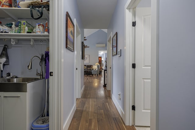 hall featuring hardwood / wood-style floors, baseboards, and a sink