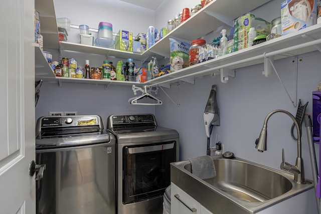 clothes washing area with washer and dryer, a sink, and cabinet space