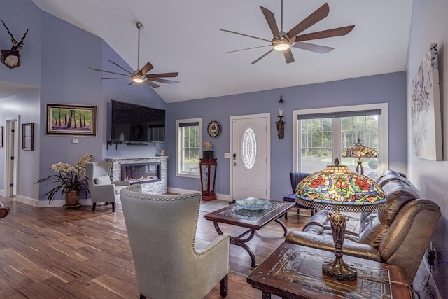 living room featuring wood finished floors, a ceiling fan, a fireplace, and lofted ceiling