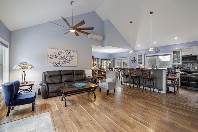living room with recessed lighting, a wall mounted air conditioner, high vaulted ceiling, a ceiling fan, and wood finished floors