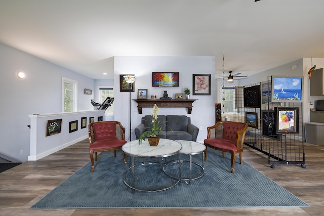 living area with baseboards, wood finished floors, a ceiling fan, and a fireplace