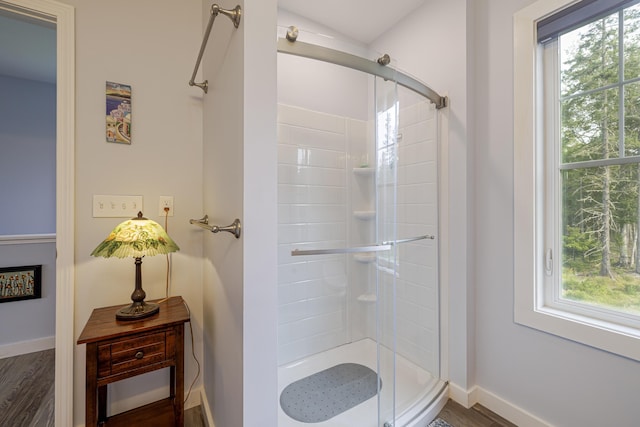 full bathroom featuring a stall shower, wood finished floors, and baseboards