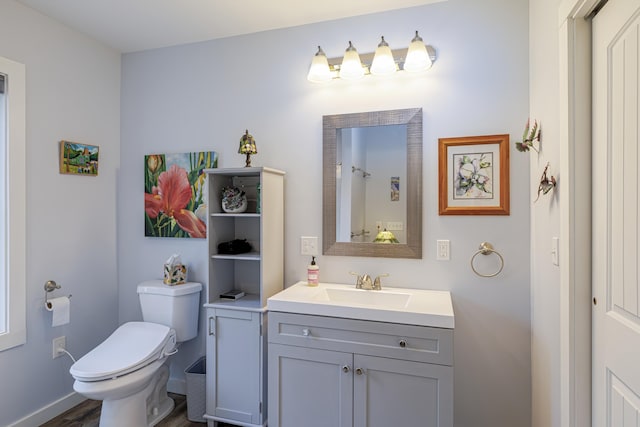 bathroom with wood finished floors, toilet, vanity, and baseboards