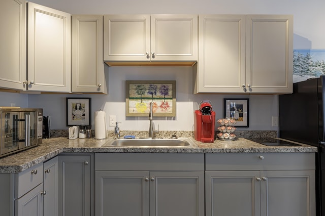kitchen with a sink, gray cabinetry, light countertops, freestanding refrigerator, and a toaster