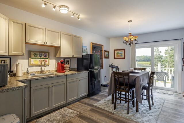 kitchen with dark wood-style flooring, a notable chandelier, freestanding refrigerator, and a sink