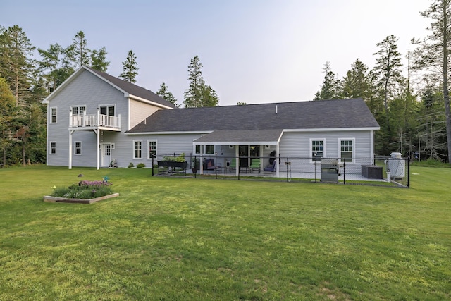 rear view of property with fence, a yard, and central air condition unit