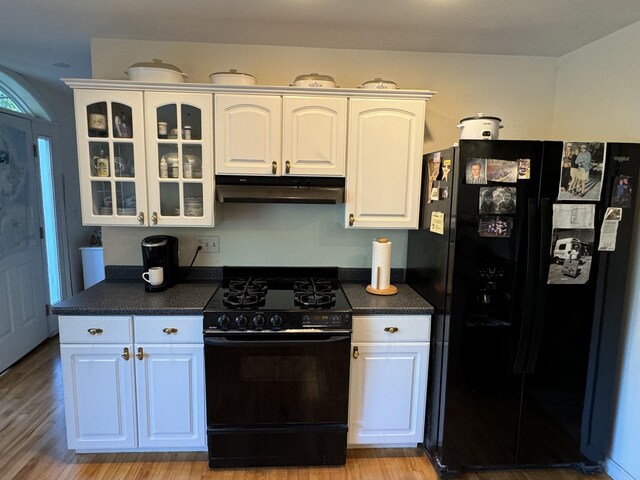 kitchen featuring black appliances, dark countertops, white cabinets, and under cabinet range hood