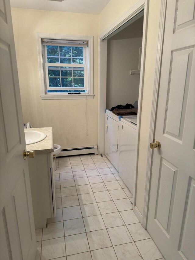 bathroom with toilet, washing machine and dryer, vanity, and a baseboard radiator