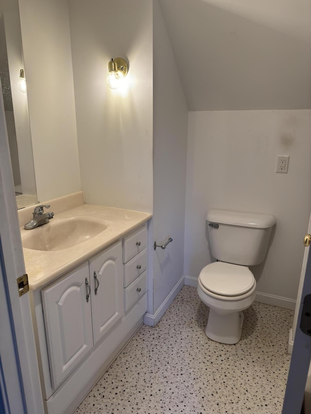 bathroom with toilet, vaulted ceiling, vanity, and baseboards