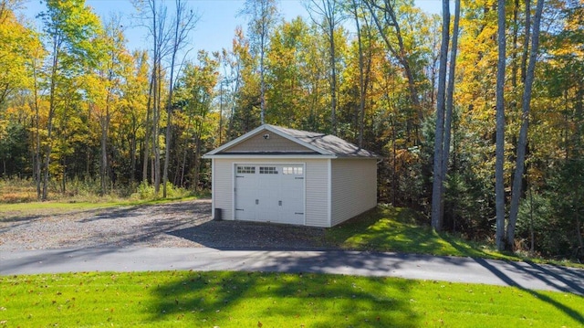 detached garage with a wooded view and gravel driveway