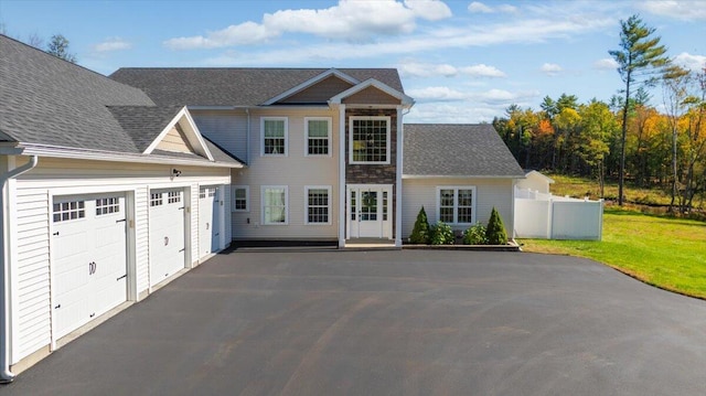 view of front of house featuring an attached garage, fence, a front lawn, and aphalt driveway