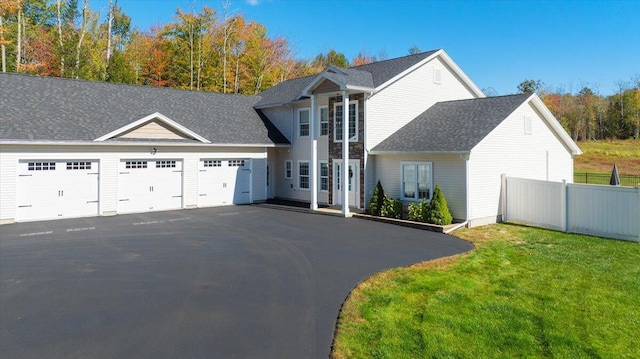 view of front of property with fence, an attached garage, a shingled roof, a front lawn, and aphalt driveway
