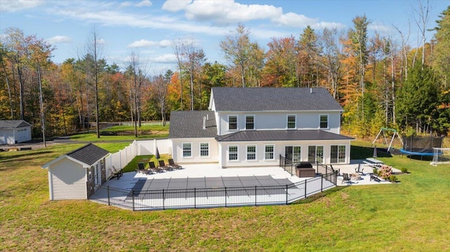 back of house with a fenced backyard, an outbuilding, a patio, and a yard