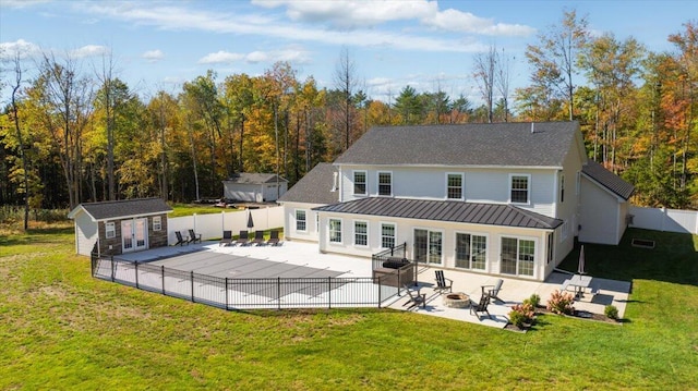 rear view of property with a standing seam roof, a fire pit, a fenced backyard, and a patio area