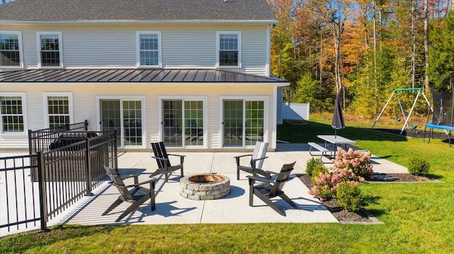 back of property with a standing seam roof, a patio area, metal roof, an outdoor fire pit, and a yard