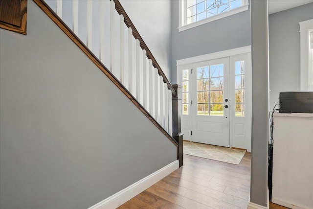 foyer featuring baseboards, wood finished floors, stairway, and a towering ceiling