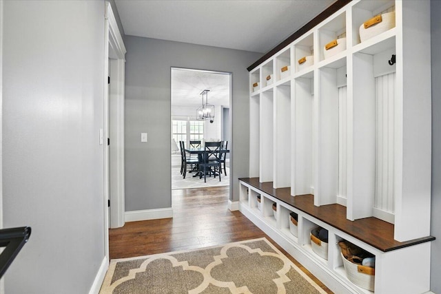 mudroom with baseboards, wood finished floors, and a chandelier