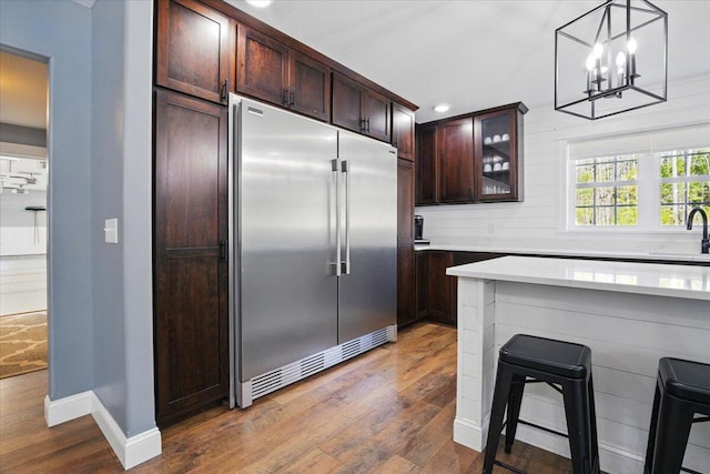 kitchen with a sink, light countertops, dark wood finished floors, and built in fridge