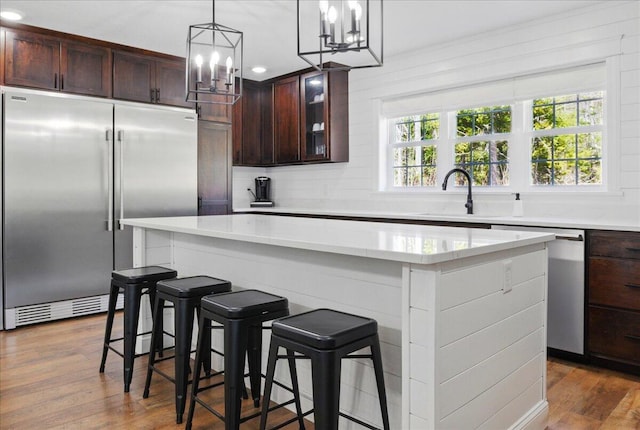 kitchen featuring appliances with stainless steel finishes, an inviting chandelier, a sink, decorative backsplash, and a kitchen island