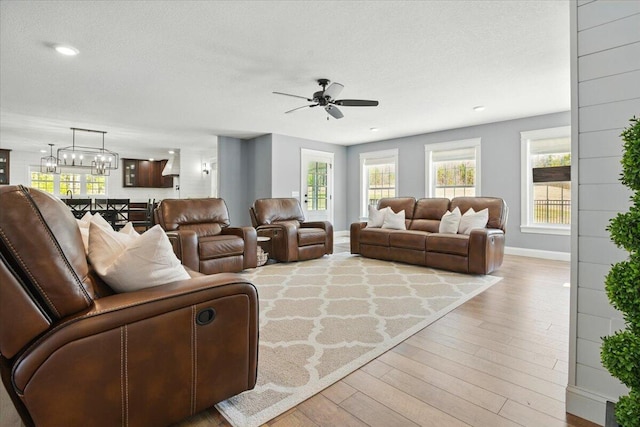 living area with a textured ceiling, wood finished floors, baseboards, ceiling fan with notable chandelier, and recessed lighting