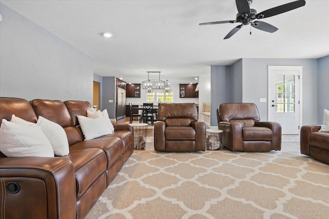 living area with ceiling fan with notable chandelier and carpet flooring