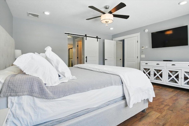 bedroom with ceiling fan, visible vents, a barn door, recessed lighting, and hardwood / wood-style floors