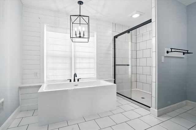 bathroom with a freestanding tub, a stall shower, baseboards, tile patterned floors, and a chandelier