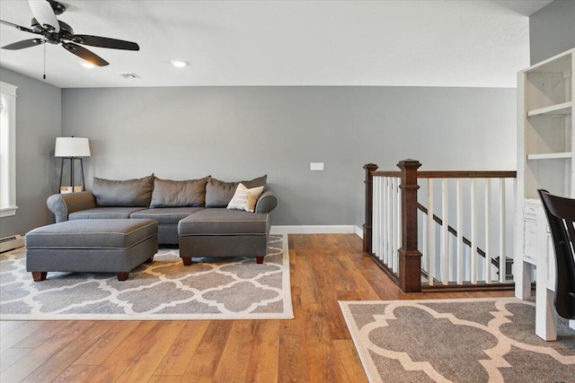 living room with wood-type flooring, a baseboard heating unit, ceiling fan, and visible vents