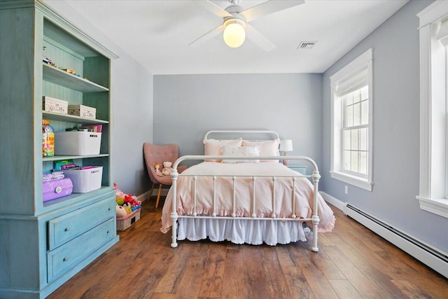 bedroom featuring a baseboard radiator, a ceiling fan, baseboards, dark wood-type flooring, and visible vents