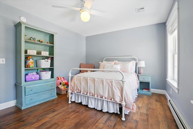 bedroom with visible vents, multiple windows, baseboard heating, and wood finished floors