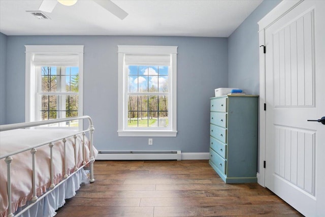 unfurnished bedroom with visible vents, wood finished floors, baseboards, a baseboard heating unit, and a ceiling fan
