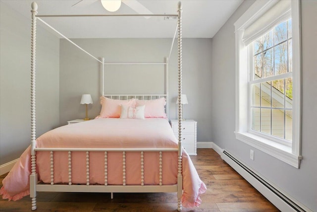 bedroom featuring baseboards, a baseboard radiator, and wood finished floors