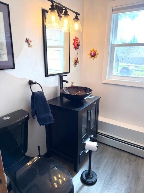 bathroom featuring vanity, baseboard heating, toilet, and wood finished floors