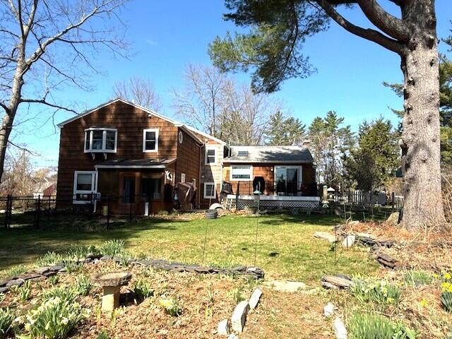 back of house featuring a lawn, fence, and a wooden deck