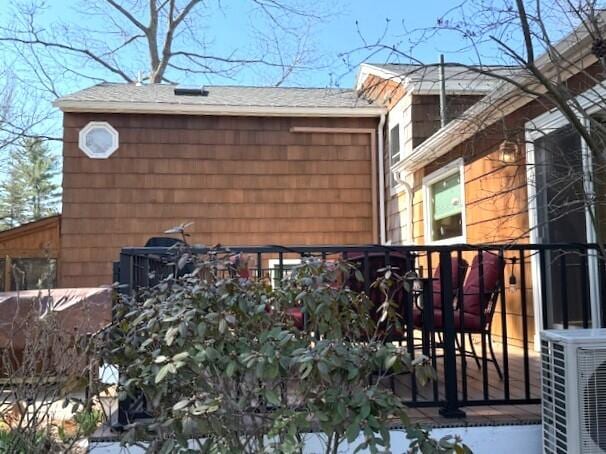 view of home's exterior featuring ac unit and roof with shingles
