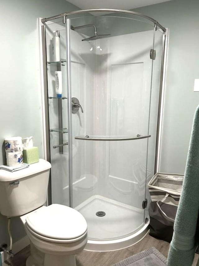 full bath with a shower stall, toilet, and wood finished floors