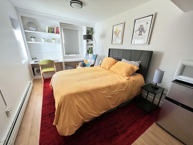 bedroom featuring wood finished floors and a baseboard heating unit