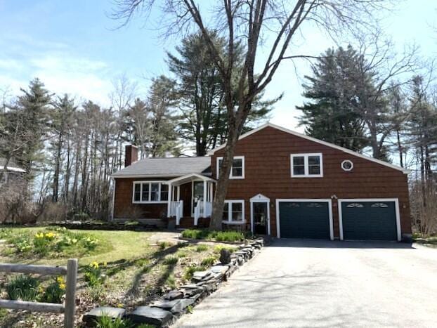 split level home featuring a garage, driveway, and a chimney
