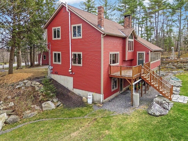 rear view of property featuring a wooden deck, a chimney, stairs, a shingled roof, and a yard
