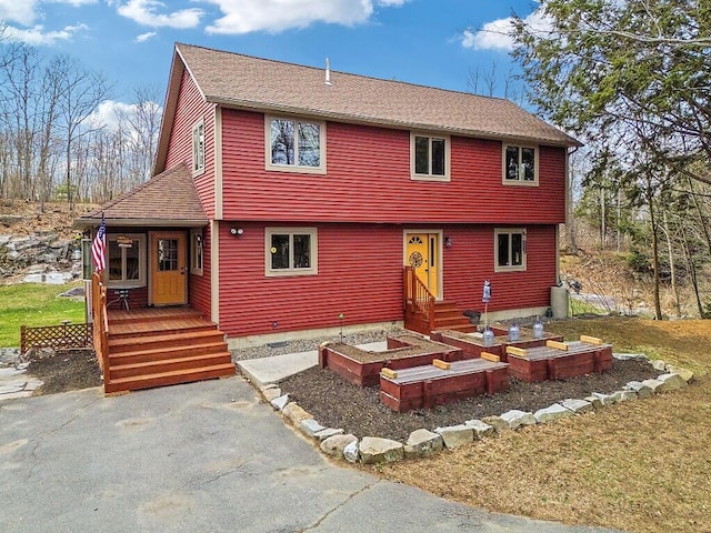 colonial house with a front lawn and roof with shingles