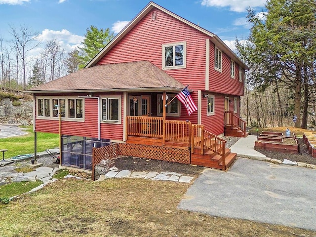 rear view of property featuring a lawn and roof with shingles