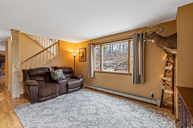 living room with wood finished floors, stairs, and a baseboard heating unit